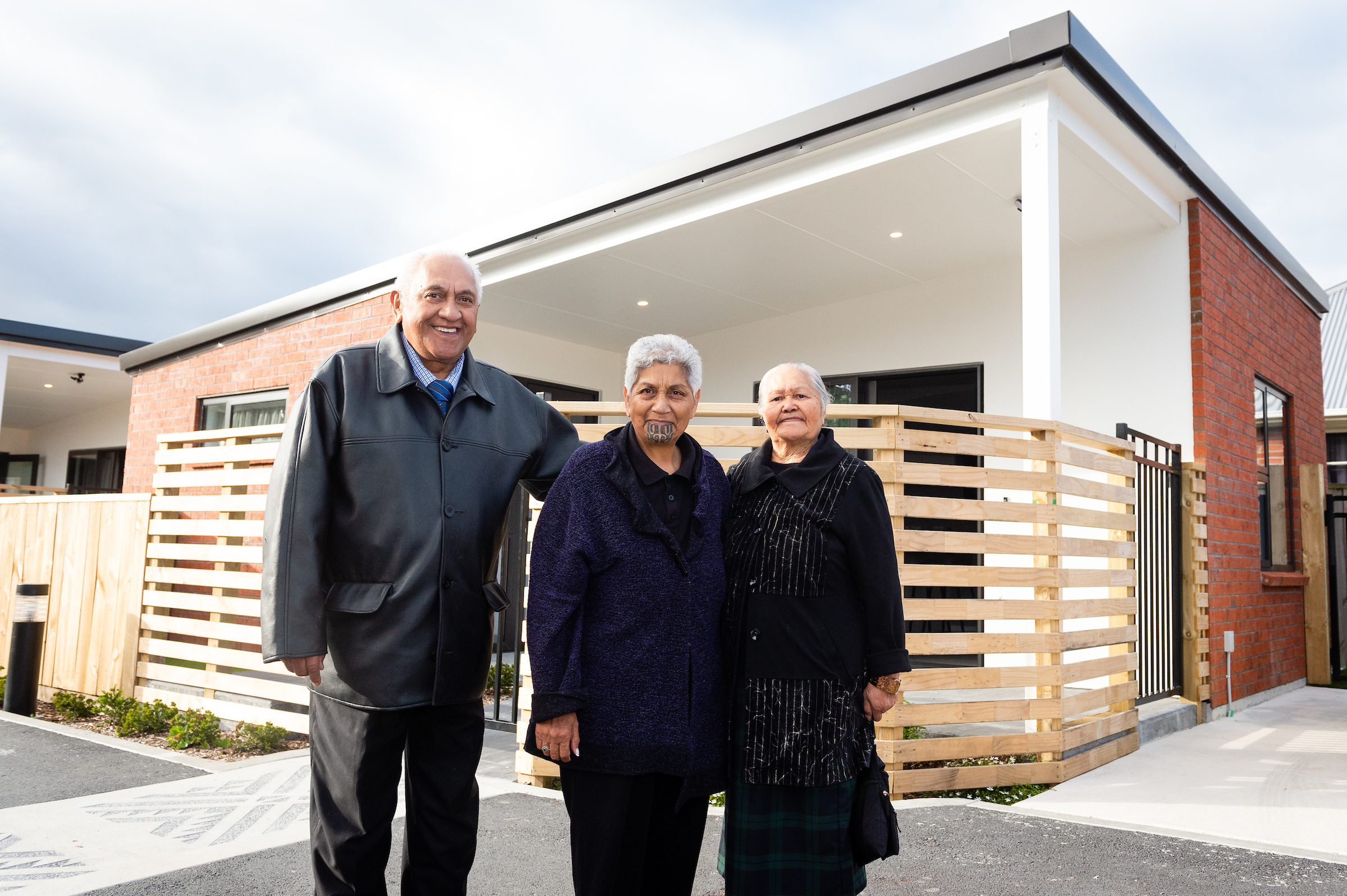 three people standing in front of a new house