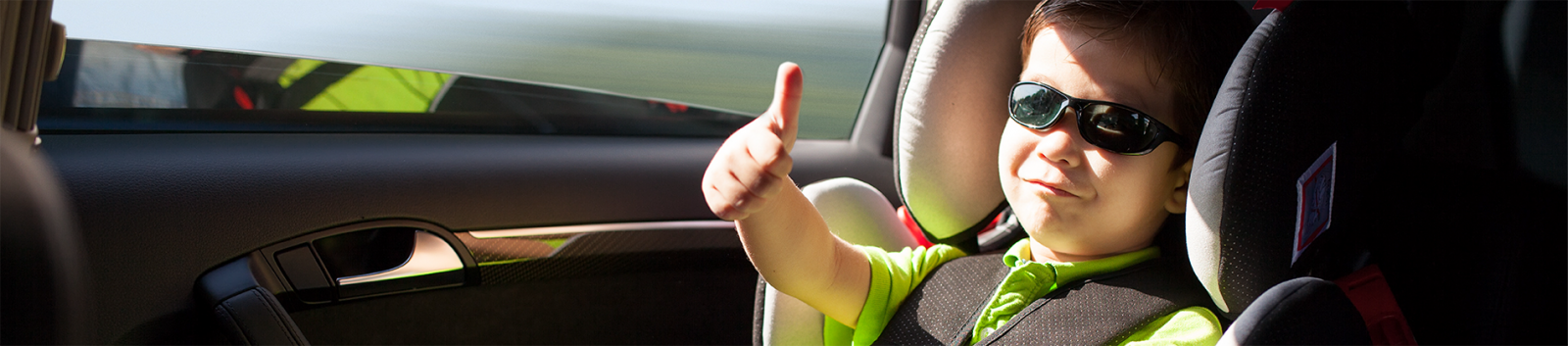 Child in carseat wearing sunglasses and giving a thumbs up banner image