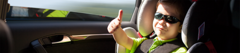 Child in carseat wearing sunglasses and giving a thumbs up