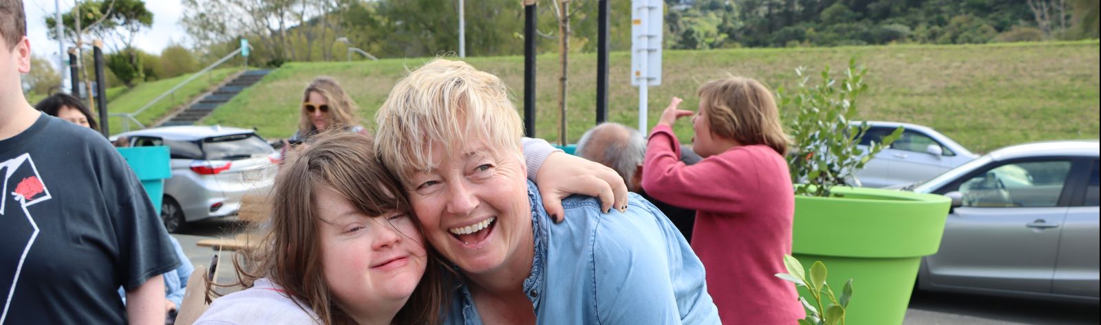 Two people smiling and planting herbs together in a raised garden bed at a community event. banner image