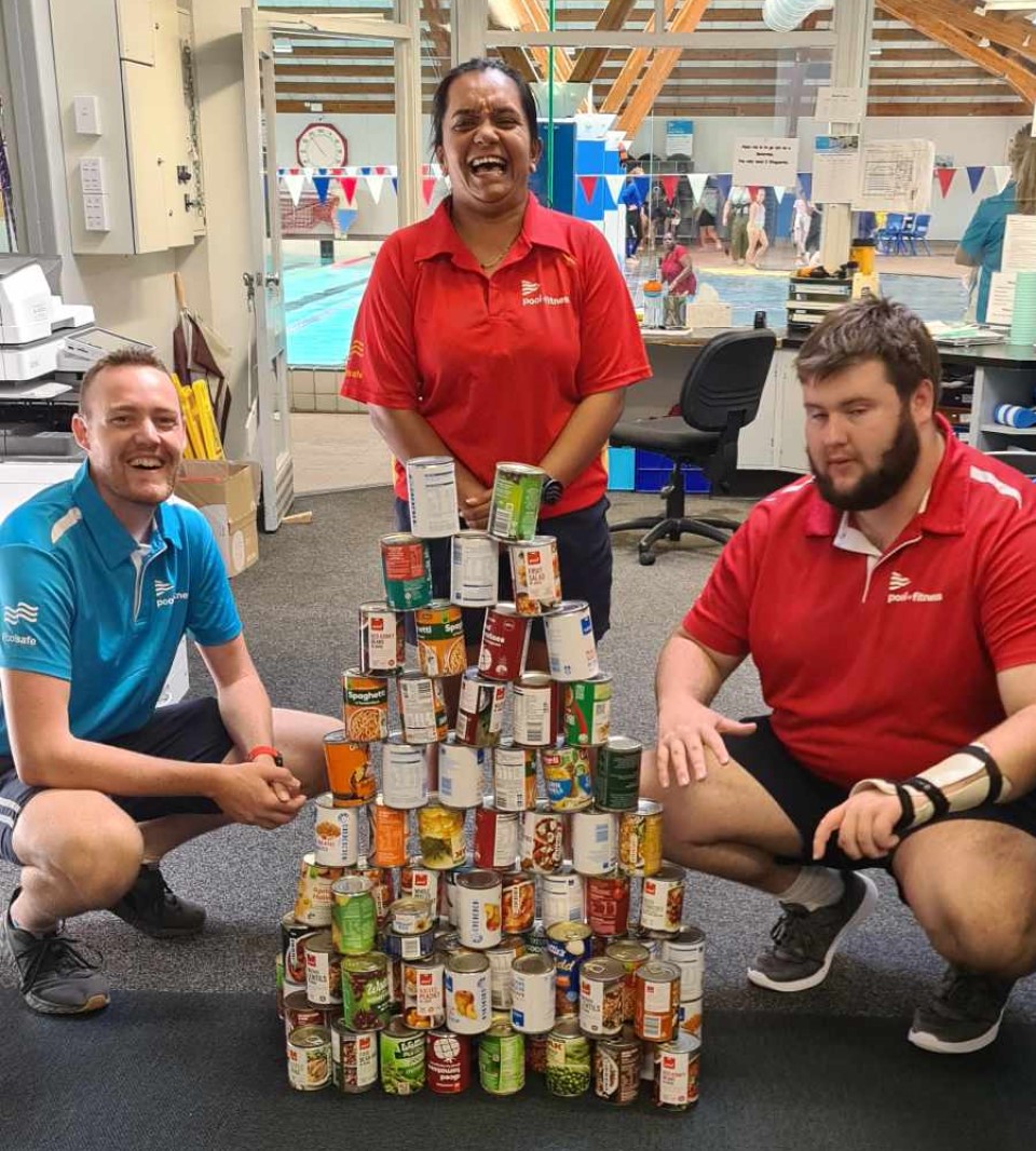 Stokes Valley lifeguards (from left) Kieran Murphy, Heli Dave, and Jared Angus with some of the 2000-plus cans that went to the Lower Hutt Foodbank.